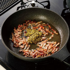 ベーコンの表面に焼き目が付いたら（３）の茹で汁をお玉１杯分加えて煮立たせ、火を止める。ジェノヴェーゼペーストを加えて混ぜておく。